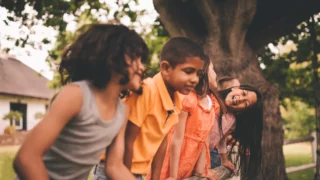 Glada barn som leker vid en ek i ett naturområde